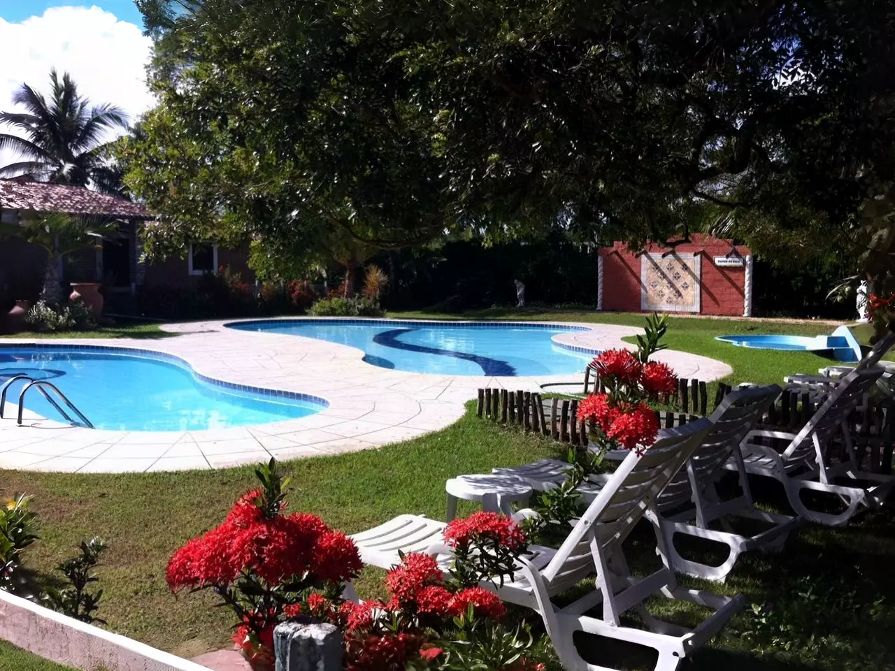 Jardim florido com piscina e espreguiçadeiras em clínica de recuperação parceira